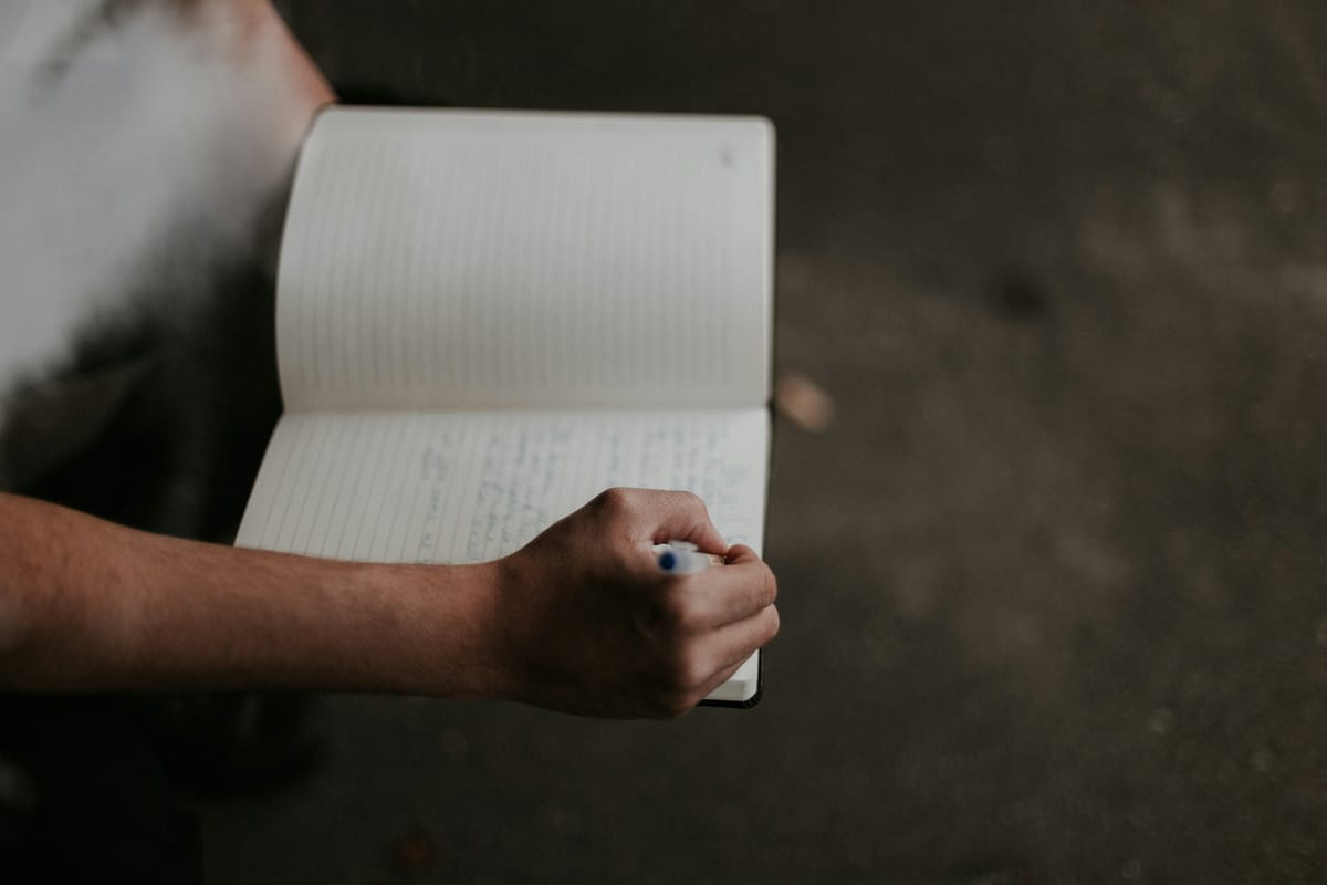 Person Writing on Paper - Importance of Note Taking